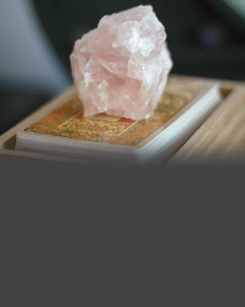 A rough piece of pale pink rose quartz on a wooden box